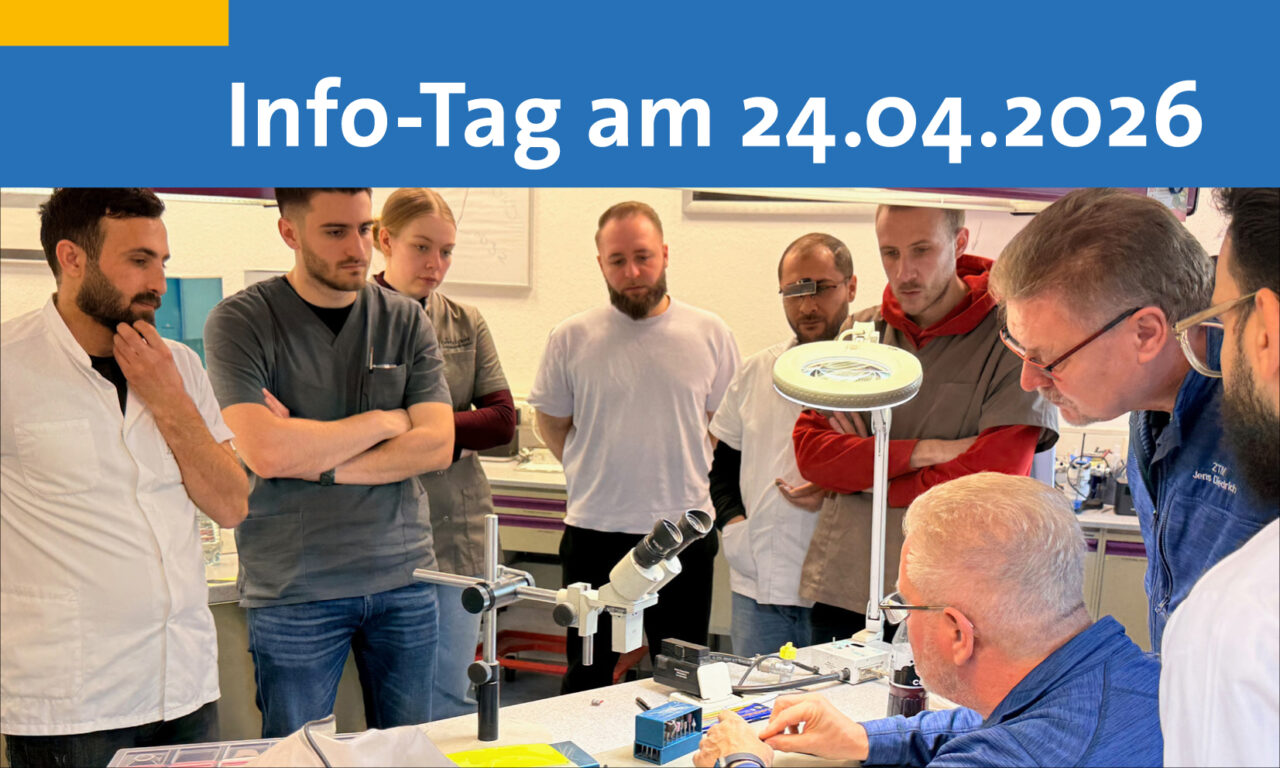 2 Dozenten am Tisch informieren 7 um sie herum stehende Interessierte über Zahntechnik.